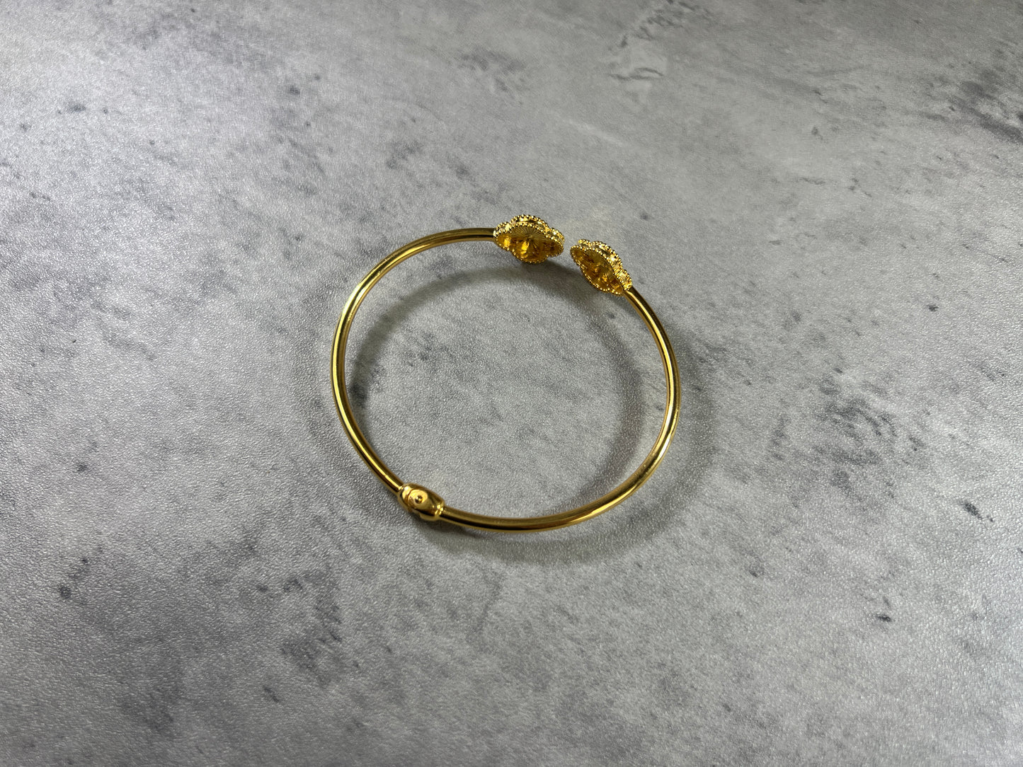 Exquisite 22ct Yellow Gold Hallmarked Bracelet—a symbol of timeless elegance. Crafted with intricate flower detailing, this highly polished piece radiates sophistication. With a cuff diameter of 6cm and two delicate clovers, it adds a touch of grace to any ensemble. Available in various sizes, please contact us for a personalized quote. Each bracelet comes beautifully packaged, making it a perfect gift choice. Embrace the allure of this finely crafted gold bracelet and elevate your style!