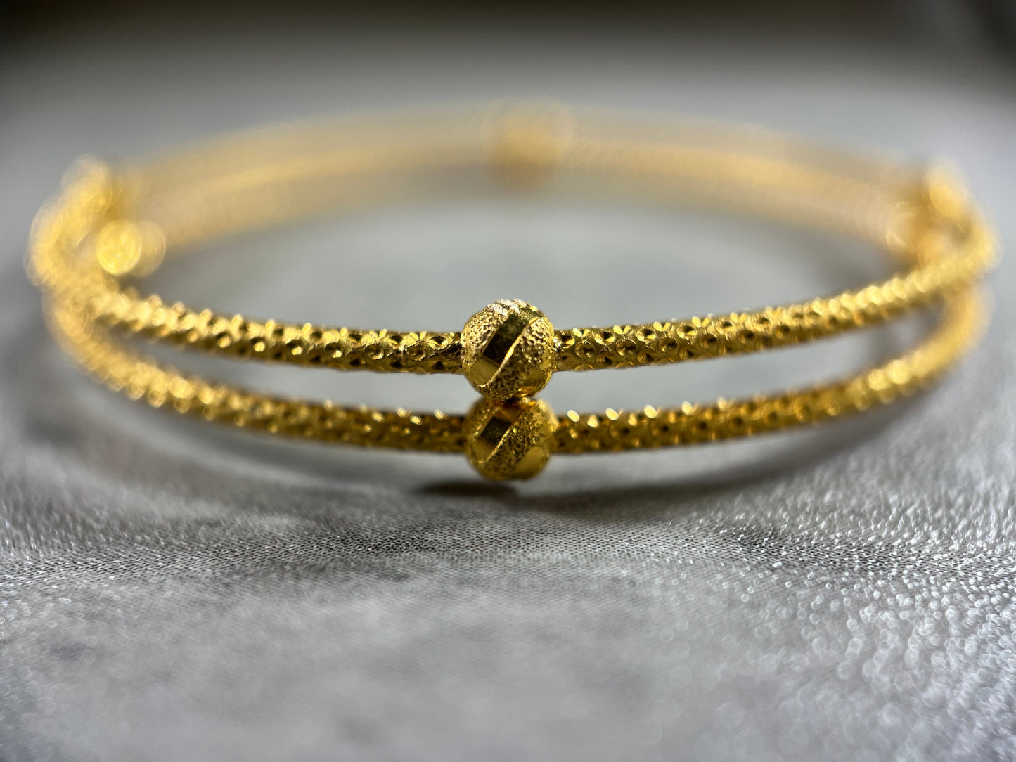 our stunning 22ct Yellow Gold Hallmarked Double Joined Bangle—an exquisite blend of craftsmanship. Its intricately hand-carved design and highly polished finish exude sophistication. With a comfortable 6cm diameter and a sleek 1.8cm width, it complements any outfit. Each bangle comes with elegant gift packaging, making it a perfect choice for yourself or a loved one. Elevate your style with this beautifully crafted gold bangle—a true symbol of timeless elegance.