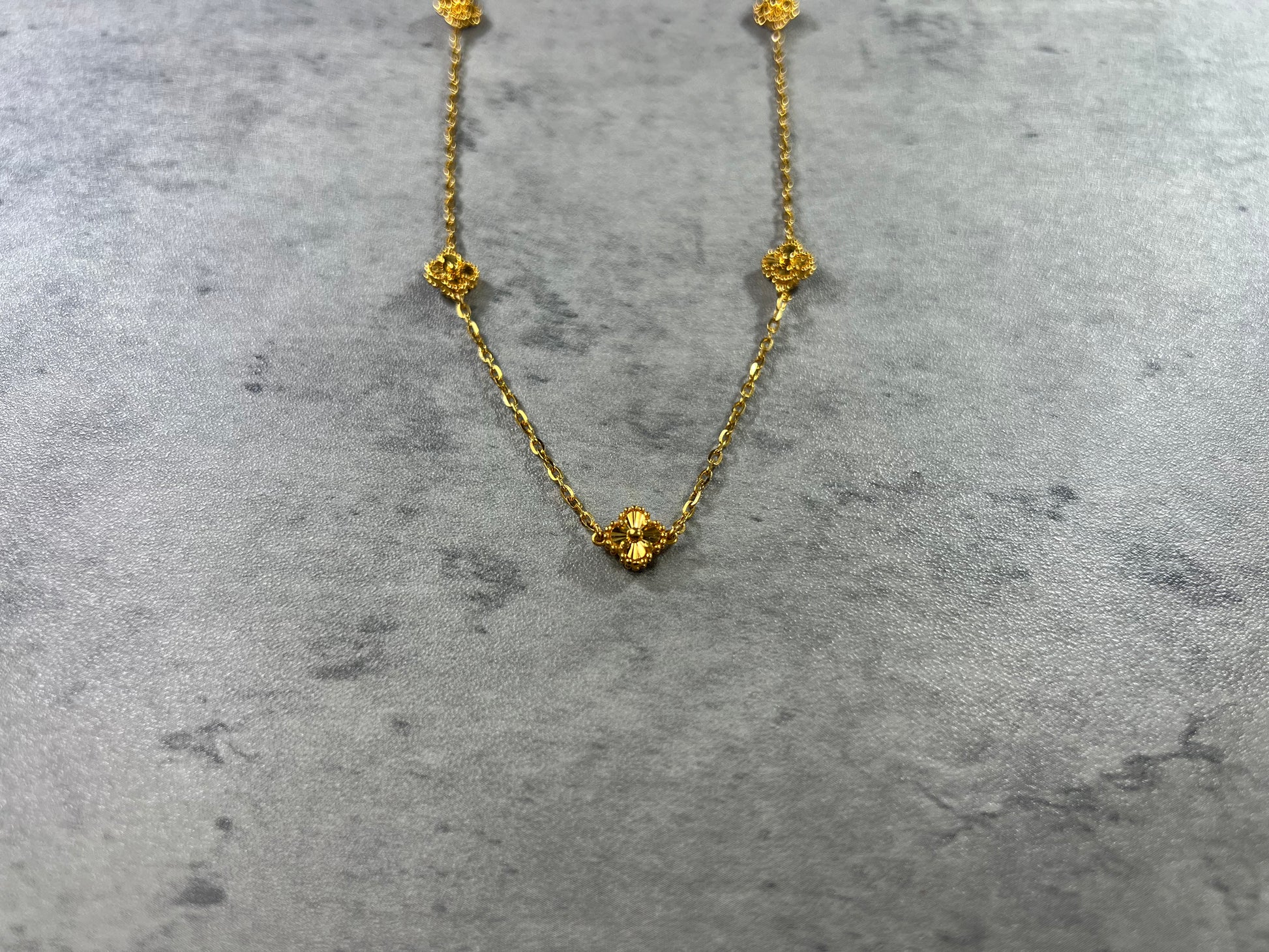 Our exquisite 22ct Yellow Gold Hallmarked Clover Necklace—a symbol of luck and beauty. This necklace features 5 delicately crafted clover designs with flower motifs and a secure Lobster Clasp. With a highly polished finish, it radiates elegance. Length: 18" (45.7cm). Also available in 3, 5, & 10 Clovers in different lengths. Elevate your style with this timeless and versatile gold necklace today.