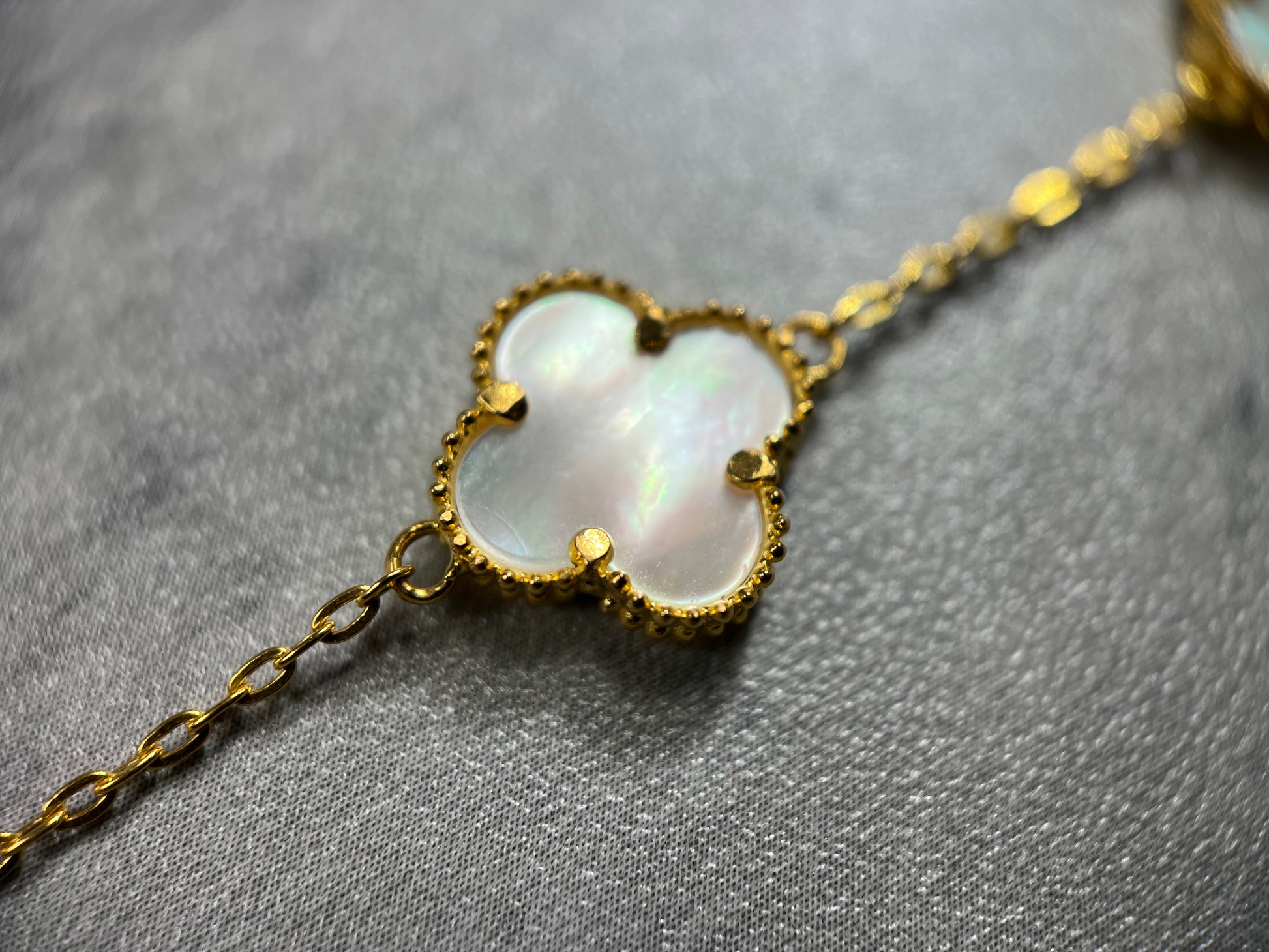 A 3 and 5 mother of pearl bracelet in 22ct yellow gold hallmarked. The design of the pearl is of a 4 petal flower, and the clasp of the bracelet is a lobster clasp. Length of bracelet is 7.5 inches. The item is ready for purchase, and is perfect as a treat for oneself, a gift for a family or friend! This bracelet is a statement piece, can be worn on its own or stacked alongside other bracelets.  Close up picture of the pearl on the bracelet