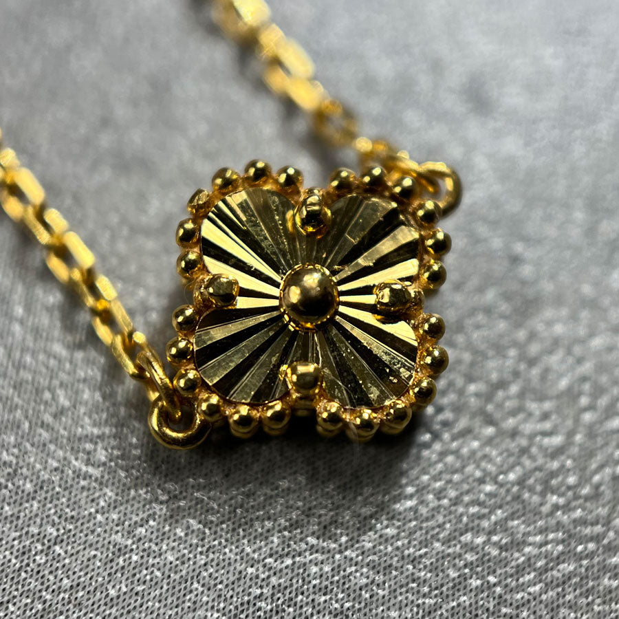 Close up picture of the clover. A 5 clover necklace in 22ct yellow gold hallmarked. The design of the necklace is of a 4 petal flower or a clover, and the clasp of the bracelet is a lobster clasp. Length of necklace is 18 inches. The item is ready for purchase, and is perfect as a treat for oneself, a gift for a family or friend! This is a statement piece, can be worn on its own or stacked alongside other necklaces. 